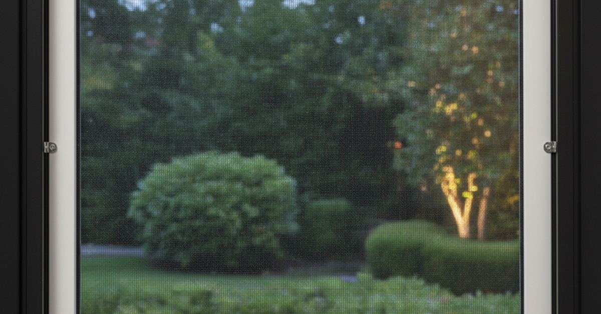 عرض كامل لنافذة مزودة بـ شبك نامس بإطار ثابت باللون الأسود، يظهر من خلاله منظر طبيعي للحديقة بوضوح.